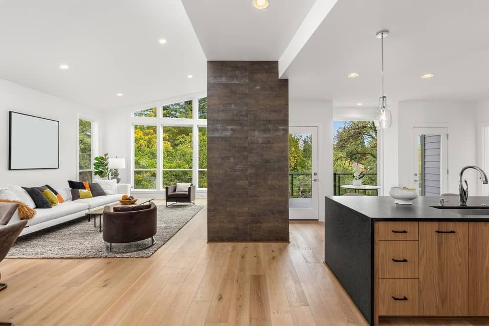 Open-concept living space with kitchen, living room, and large windows with a view of trees.
