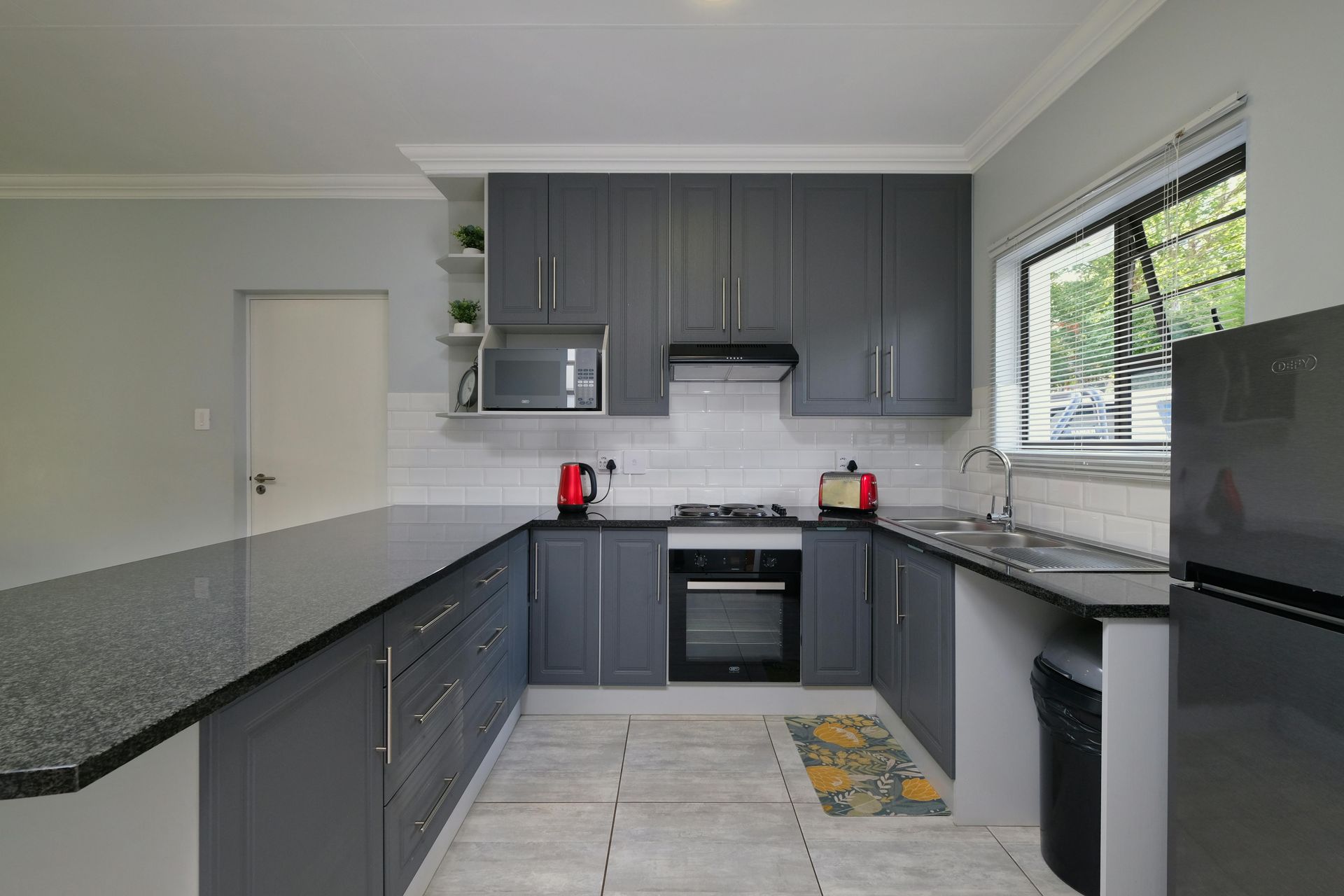 Dark gray kitchen with granite counters, cabinets, and appliances.