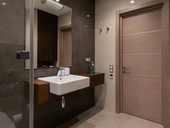 Modern bathroom with brown and tan tones; floating vanity, large mirror, and closed door.