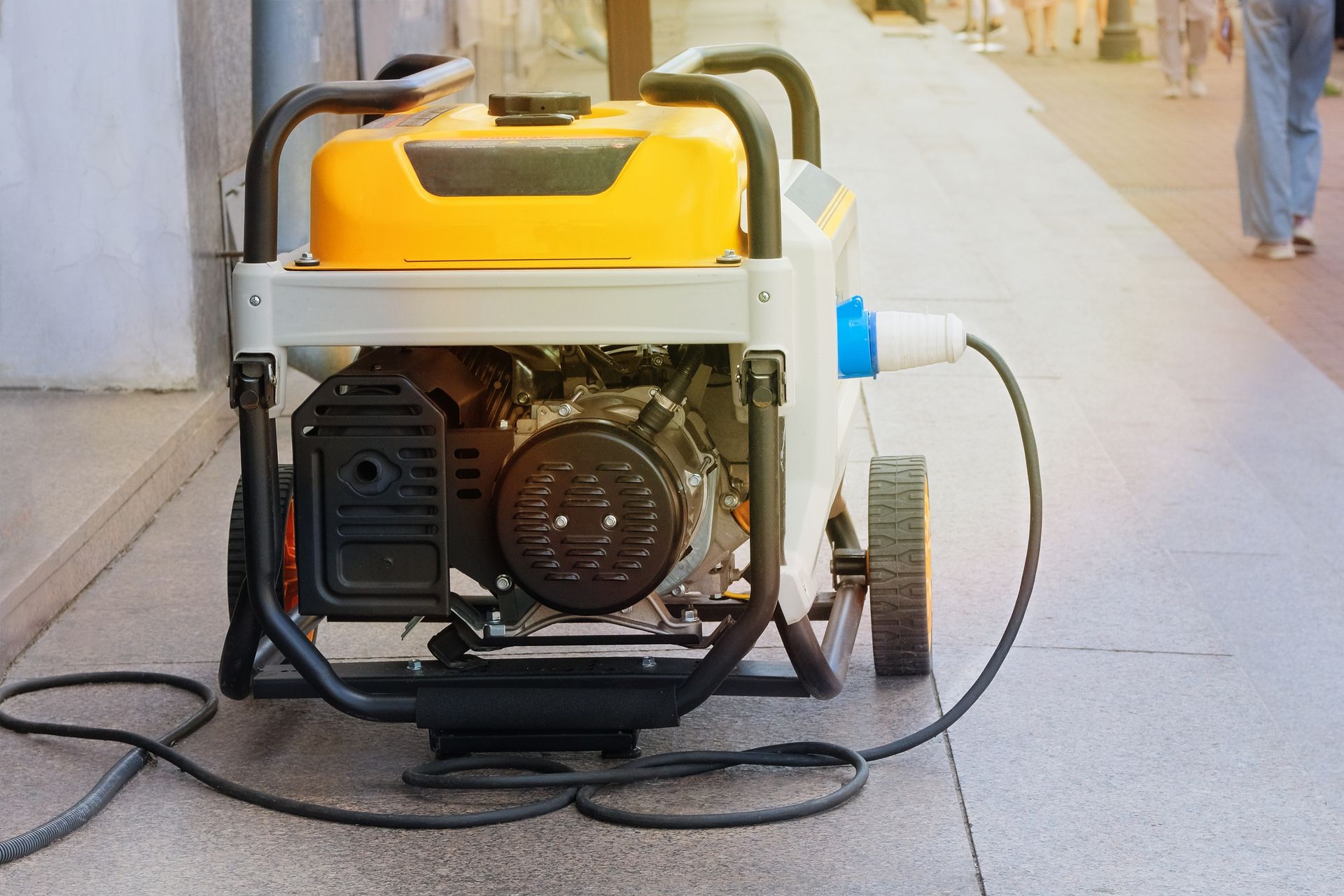 A yellow and white generator is sitting on the sidewalk.
