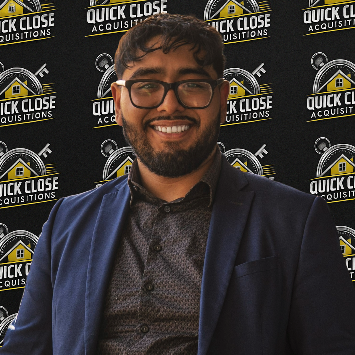A man wearing glasses is smiling in front of a wall that says quick close