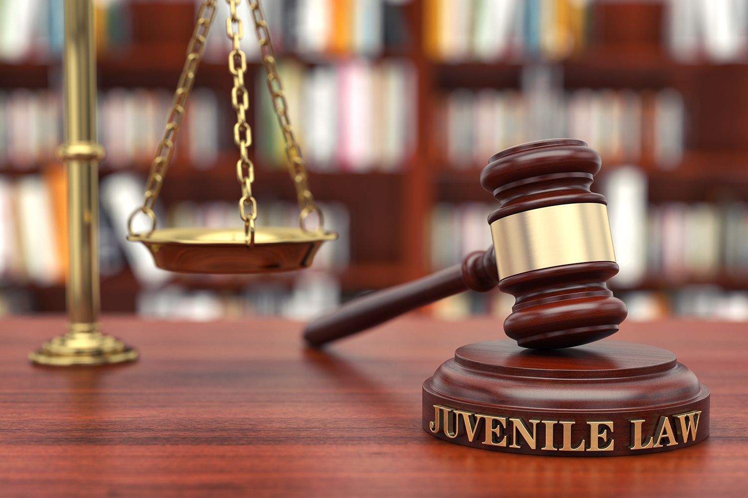 Juvenile law gavel and scales on a courtroom desk with blurred law books in the background Juvenile law gavel and scales on a courtroom desk with blurred law books in the background