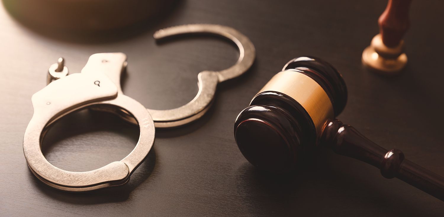 Handcuffs and a judge’s gavel on a wooden surface, symbolizing law and justice Handcuffs and a judge’s gavel on a wooden surface, symbolizing law and justice