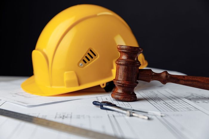 Yellow hard hat and judge’s gavel on paperwork, symbolizing workplace safety and legal issues Yellow hard hat and judge’s gavel on paperwork, symbolizing workplace safety and legal issues