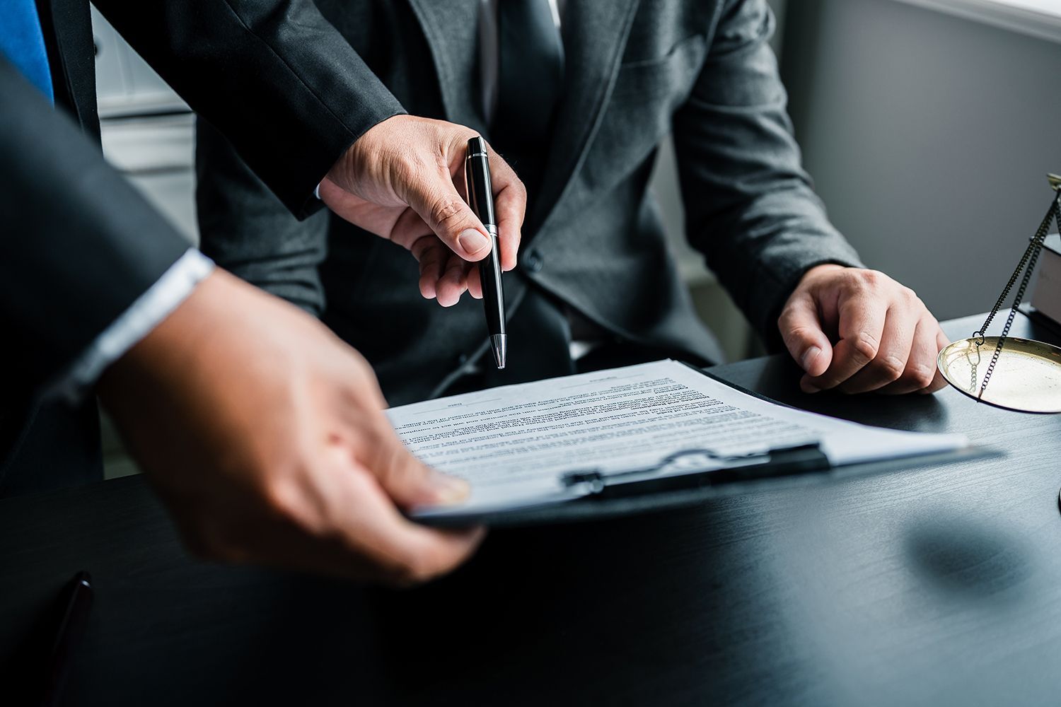 Two people reviewing a document at a desk, one pointing with a pen Two people reviewing a document at a desk, one pointing with a pen