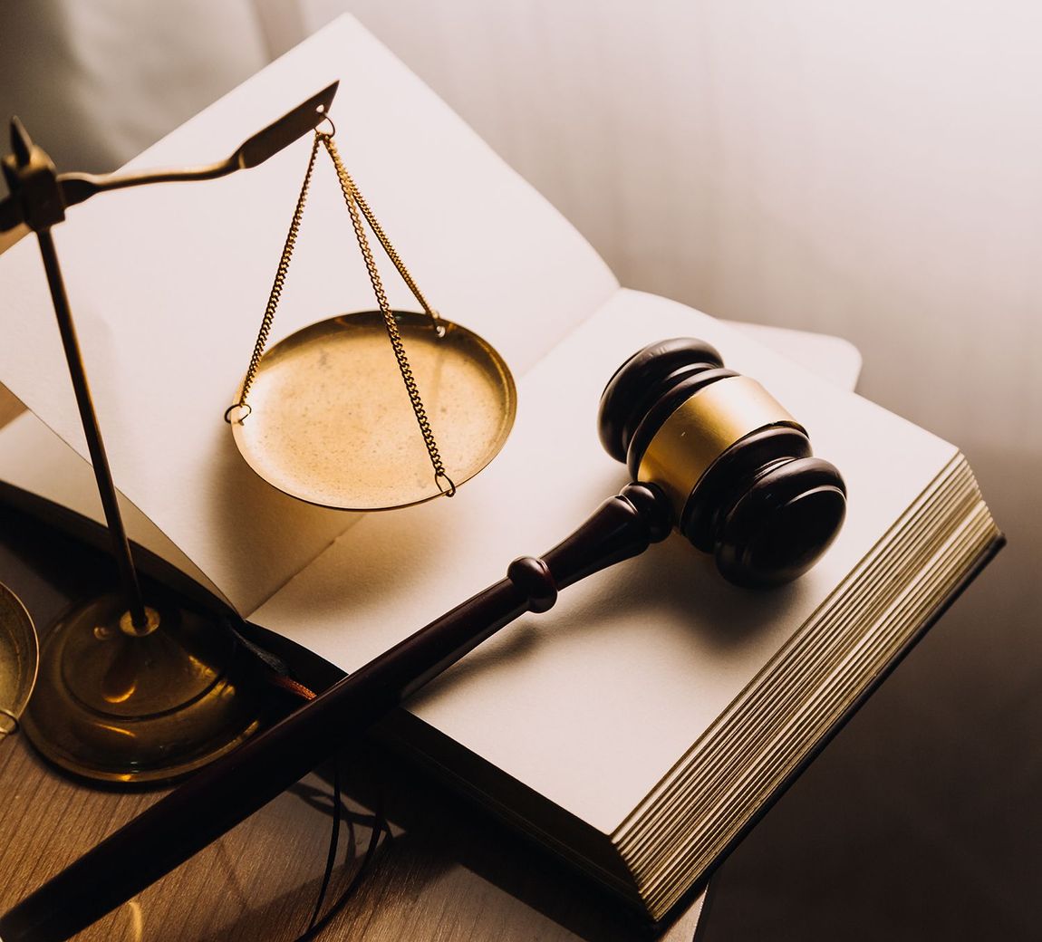 Law scales and gavel resting on open legal book, warm-toned courtroom concept Law scales and gavel resting on open legal book, warm-toned courtroom concept