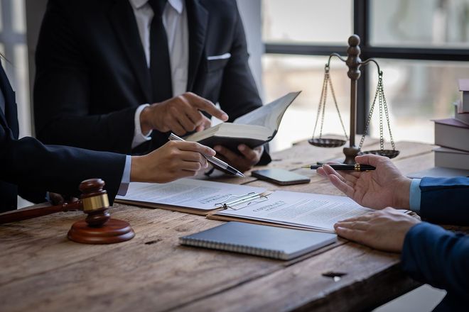 Lawyers reviewing documents at a desk with a gavel and scales of justice Lawyers reviewing documents at a desk with a gavel and scales of justice