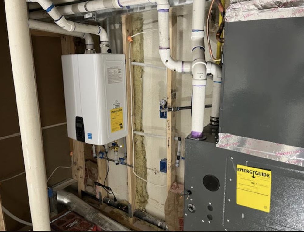 White tankless water heater and HVAC unit in a utility room with exposed pipes and wooden framing.