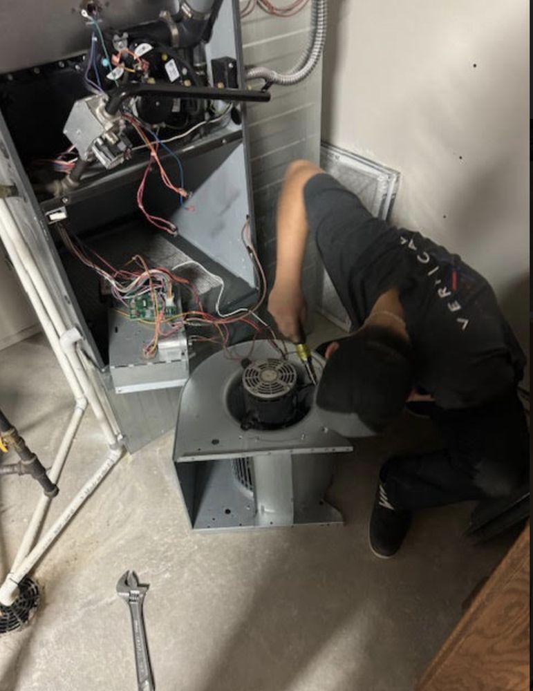 HVAC technician working on a furnace, in a basement.