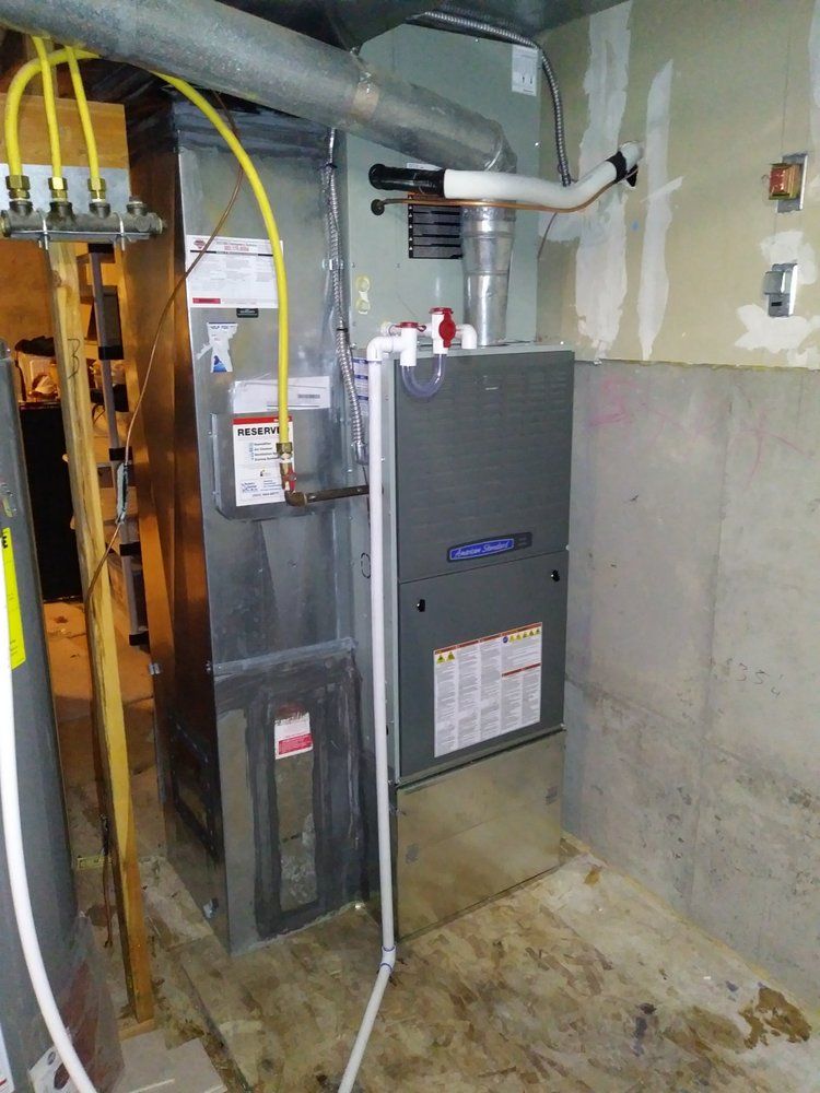 Furnace in a basement, with gas line, vent pipe, and water heater visible.