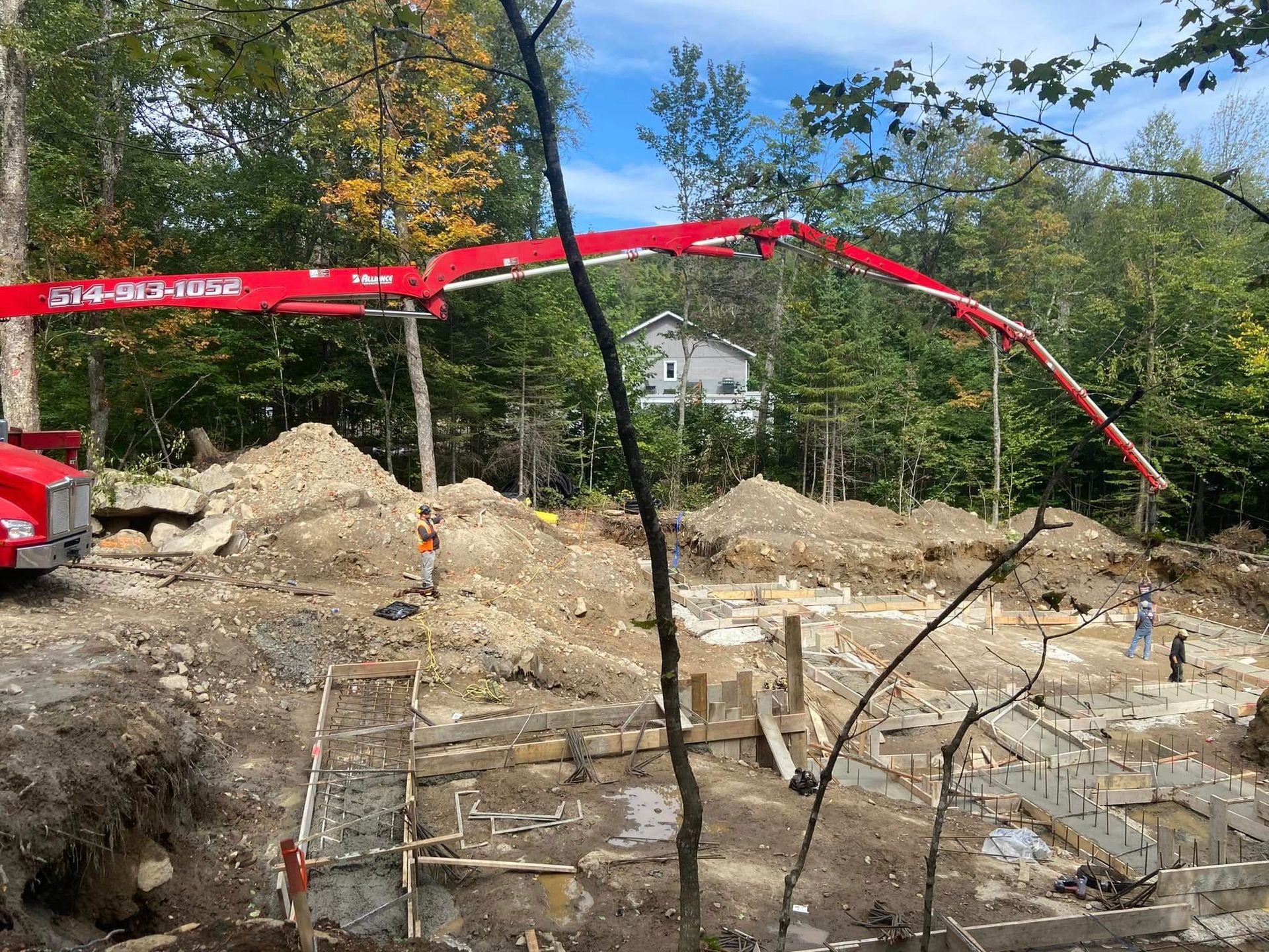 Une pompe à béton rouge est utilisée pour pomper du béton dans un champ de terre.