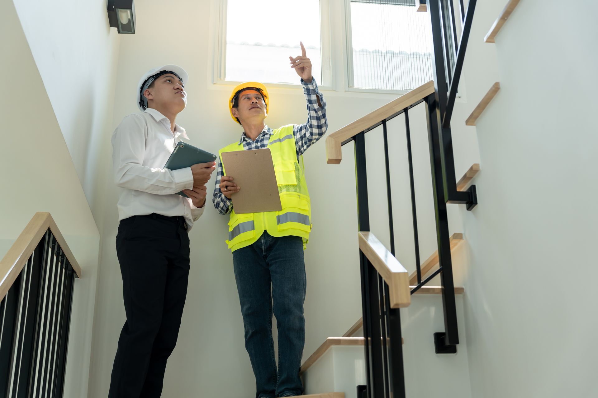 Deux hommes se tiennent sur un escalier et regardent quelque chose.
