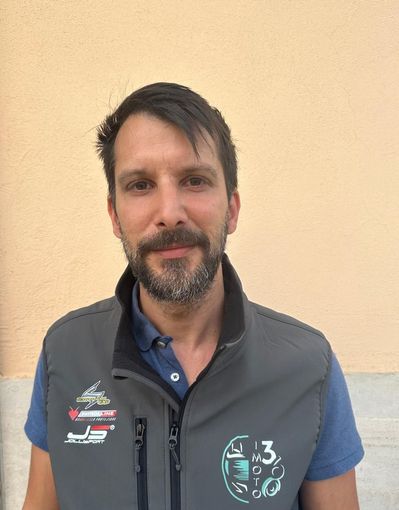 Una persona con la barba corta, che indossa una polo blu e un gilet grigio con cerniera, è in piedi