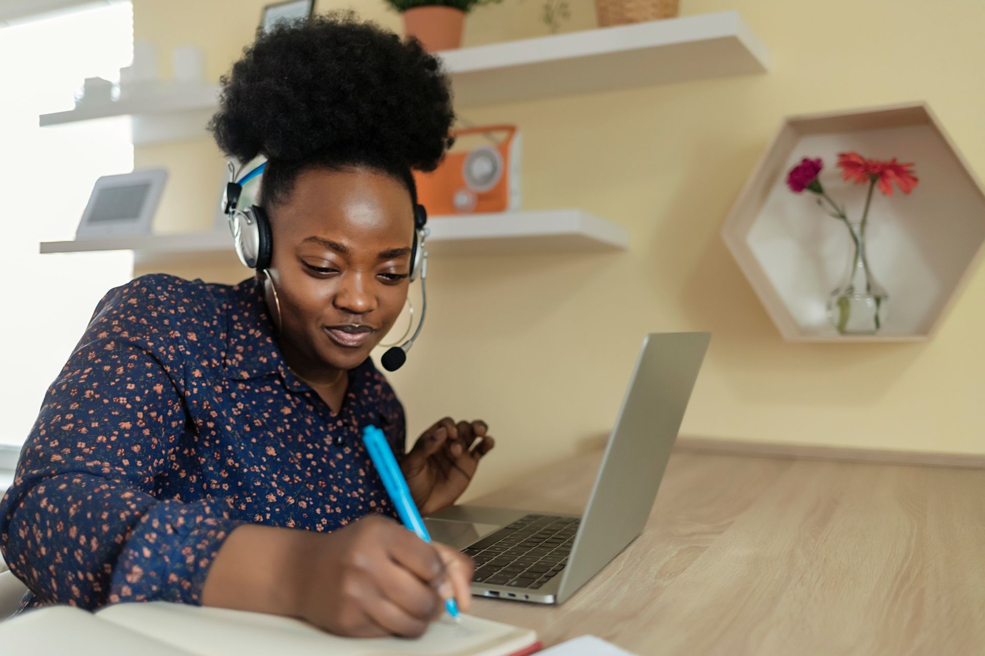 A woman wearing headphones and a headset is sitting in front of a laptop computer.