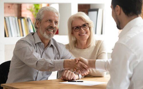 elder couple shaking hands with planner