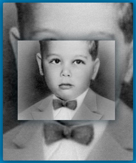 A black and white photo of a young boy in a suit and bow tie