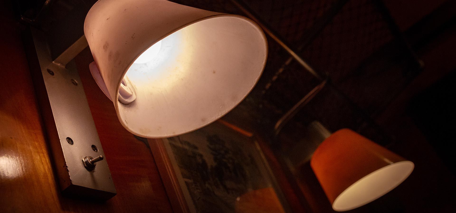 a lamp with a white shade is lit up in a dark room