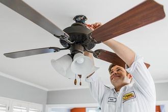 a mr sparky electrician in a white shirt is fixing a ceiling fan