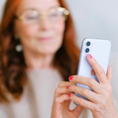 a woman with red nails is holding a cell phone