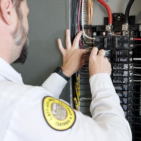 Mister Sparky Electrician in a white shirt checking overloaded circuit breakers