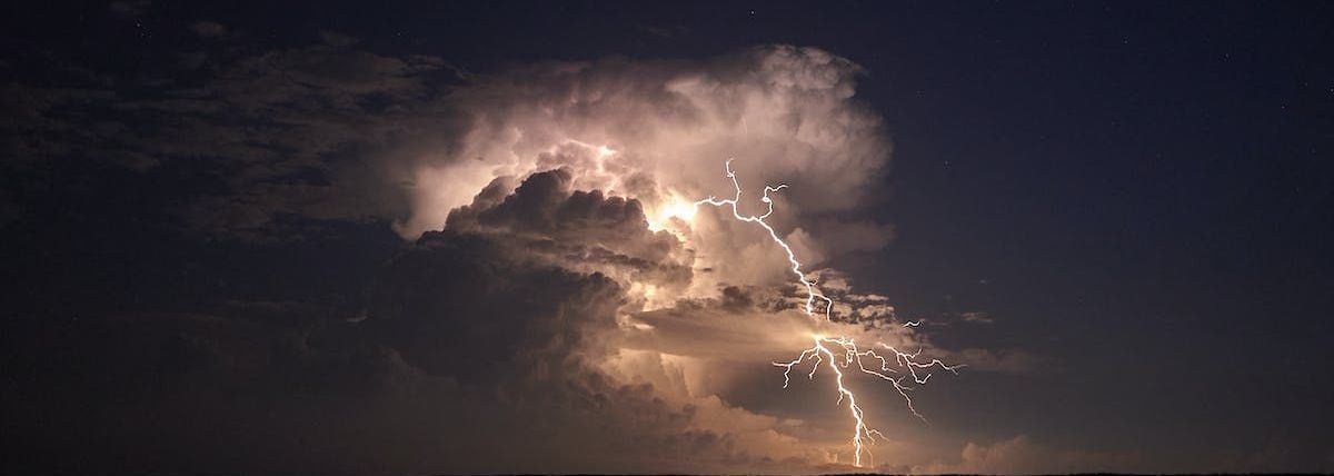 lightning strikes from a cloud in the night sky