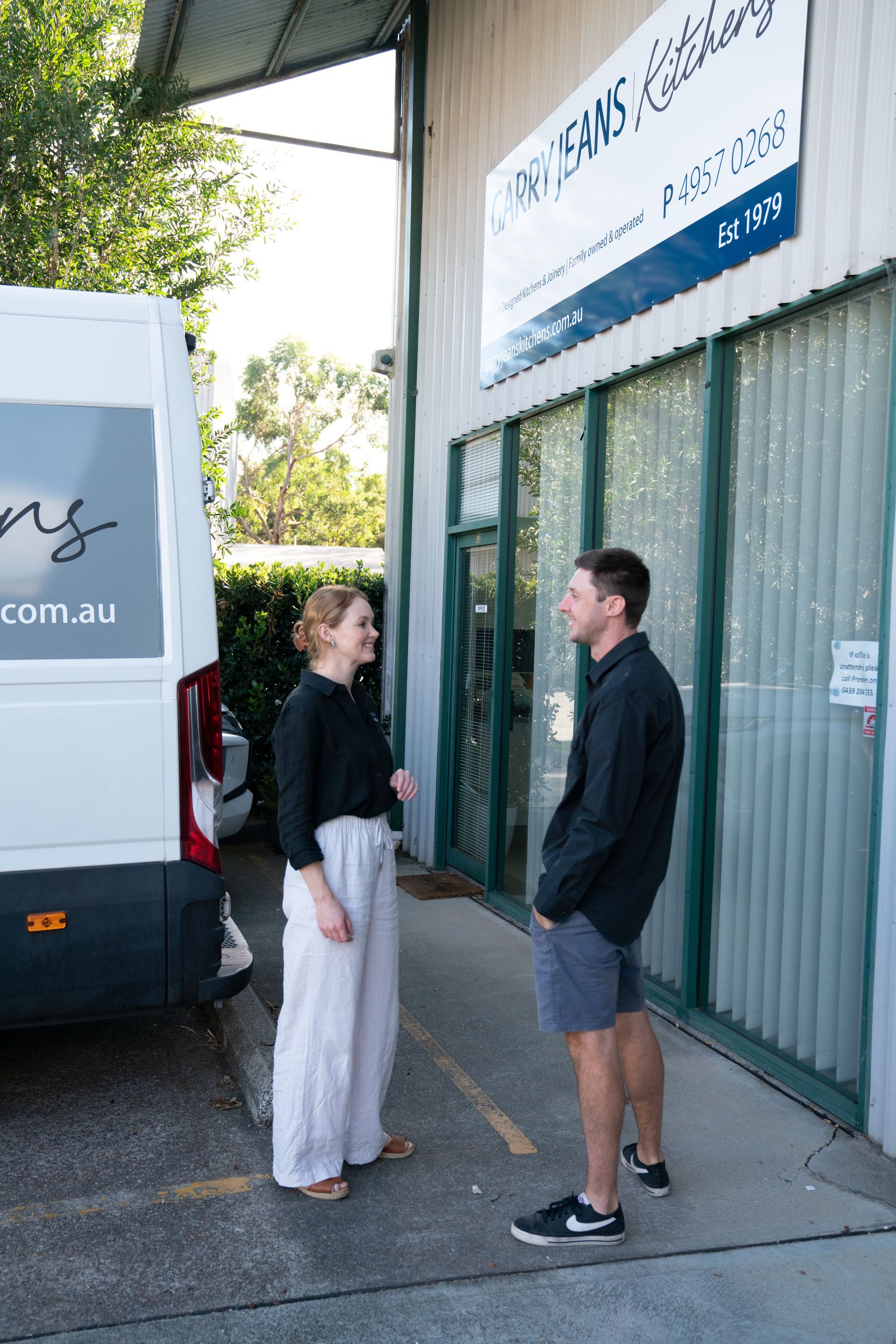 A Man And A Woman Are Looking At A Potted Plant On A Counter — Garry Jeans Kitchens In Cardiff, NSW