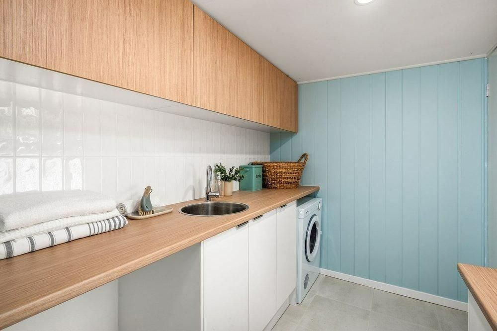 A Laundry Room With Blue Wall and Washing Machine — Garry Jeans Kitchens In Lake Macquarie, NSW
