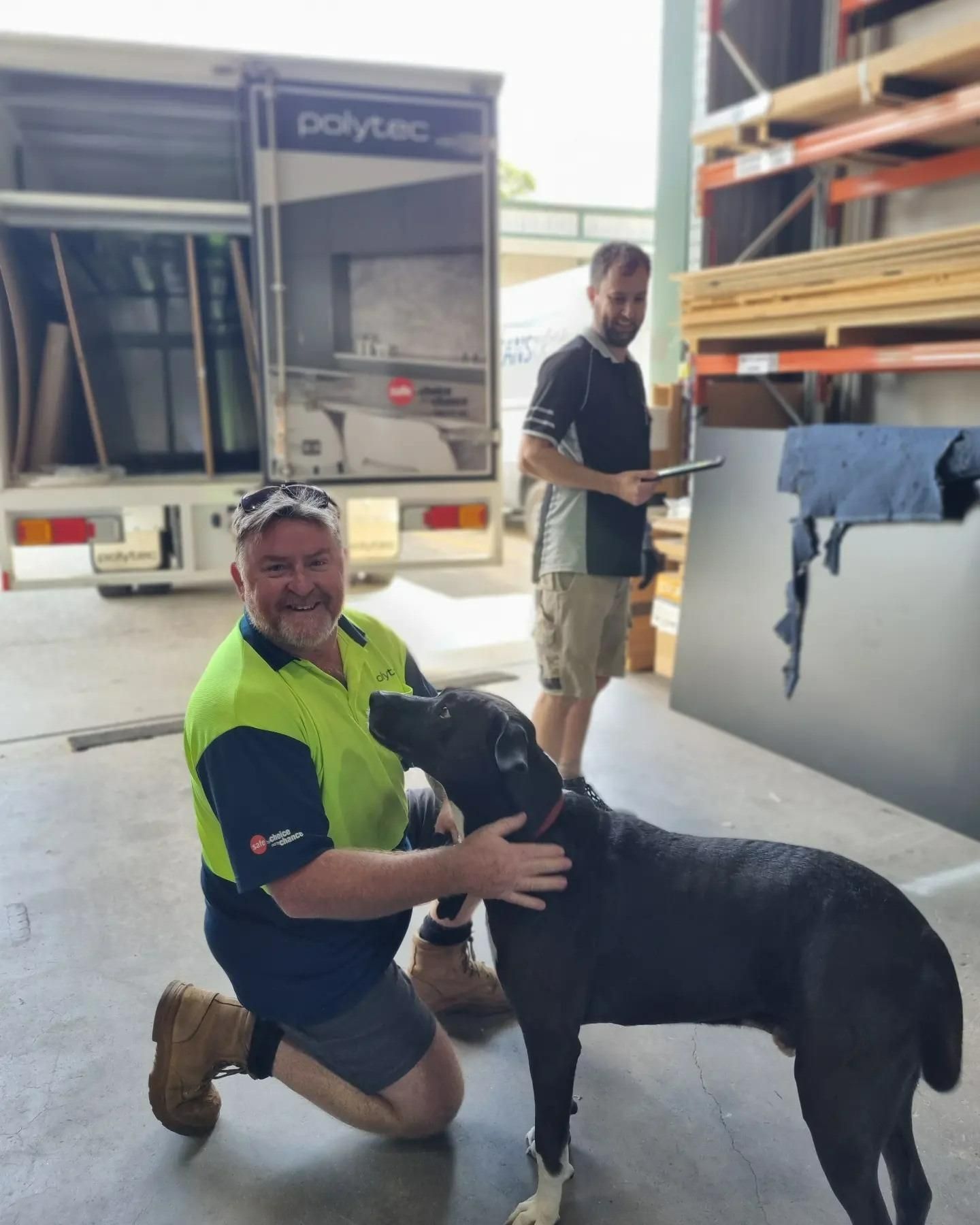 A Man Petting A Black Dog In Front Of A Dorytec Truck — Garry Jeans Kitchens In Lake Macquarie, NSW
