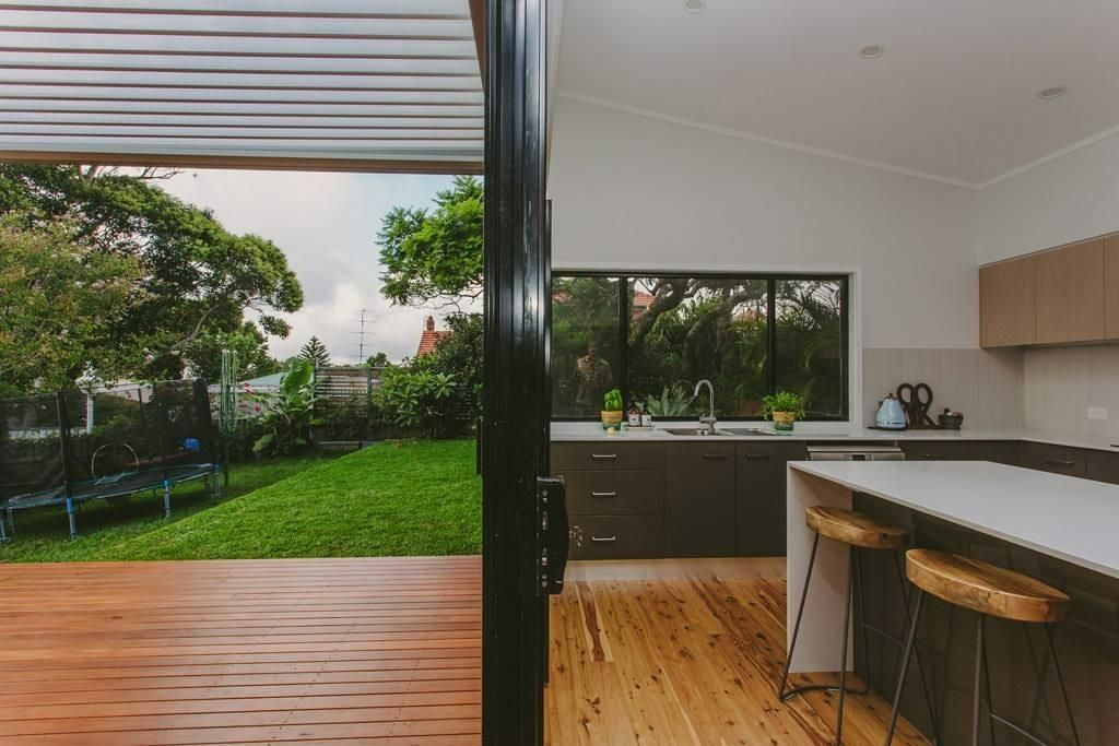 A Kitchen With A Wooden Floor And A Sliding Glass Door Leading To A Deck — Garry Jeans Kitchens In Newcastle, NSW