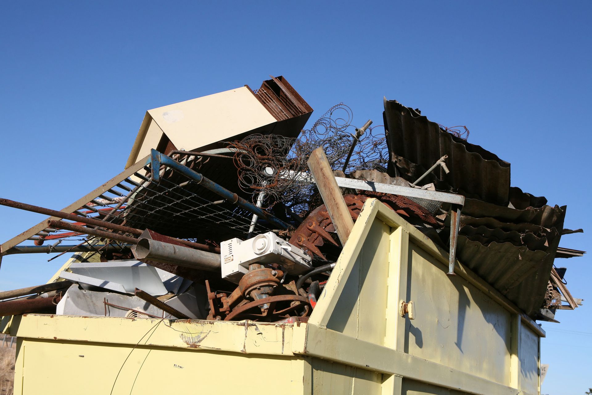 A yellow dumpster filled with a pile of scrap metal