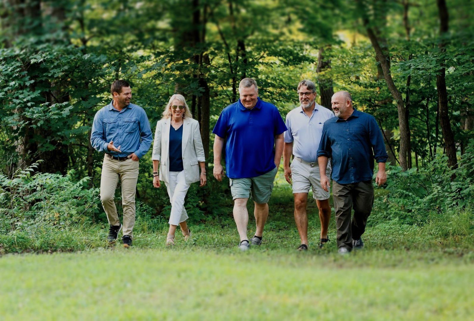 A group of people are walking through the woods.