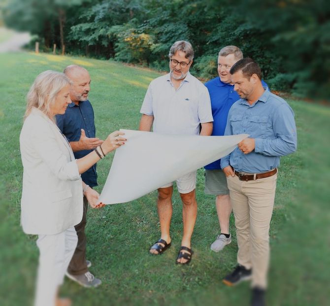 A group of people are standing in the grass looking at a piece of paper