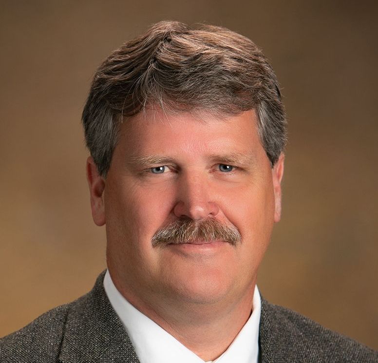 A man with a mustache is wearing a suit and tie