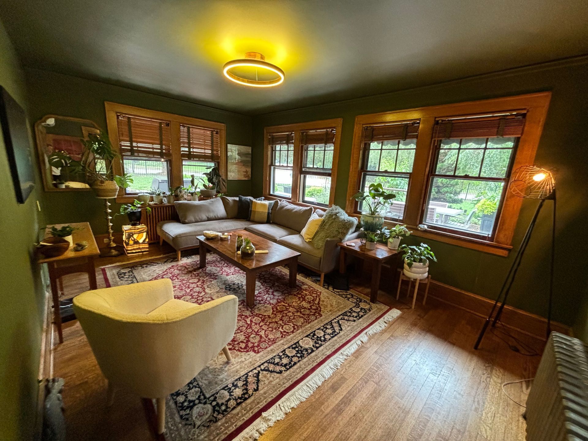 A living room with green walls , a couch , a chair , a coffee table and a rug.