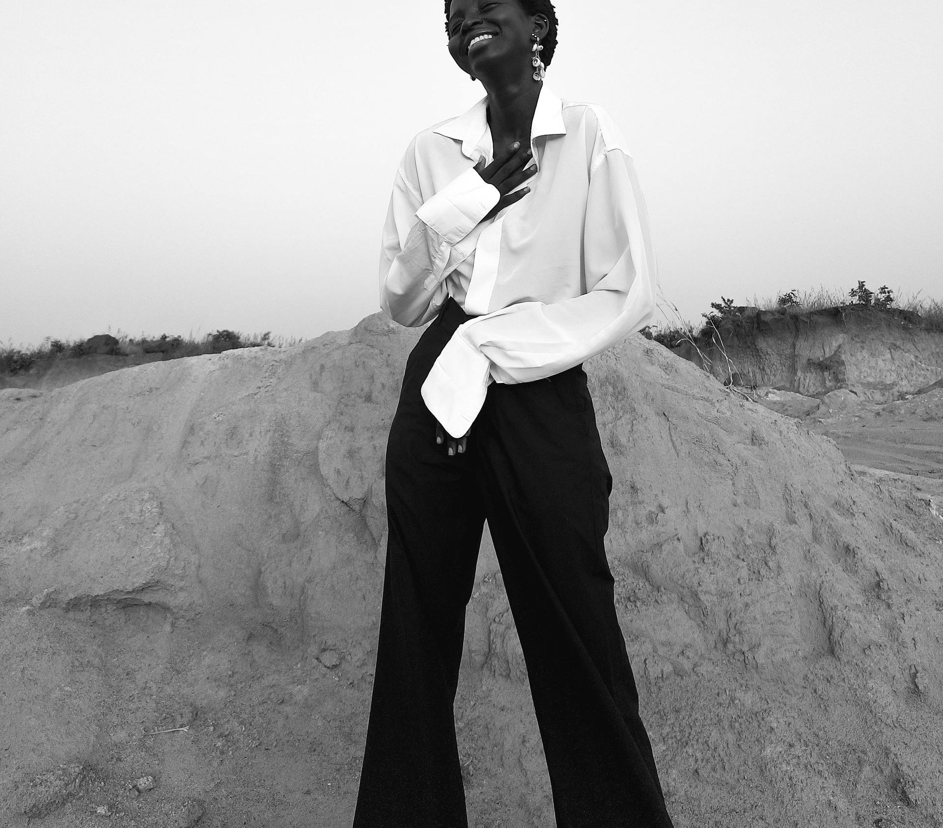 A black and white photo of a woman standing in front of a pile of sand