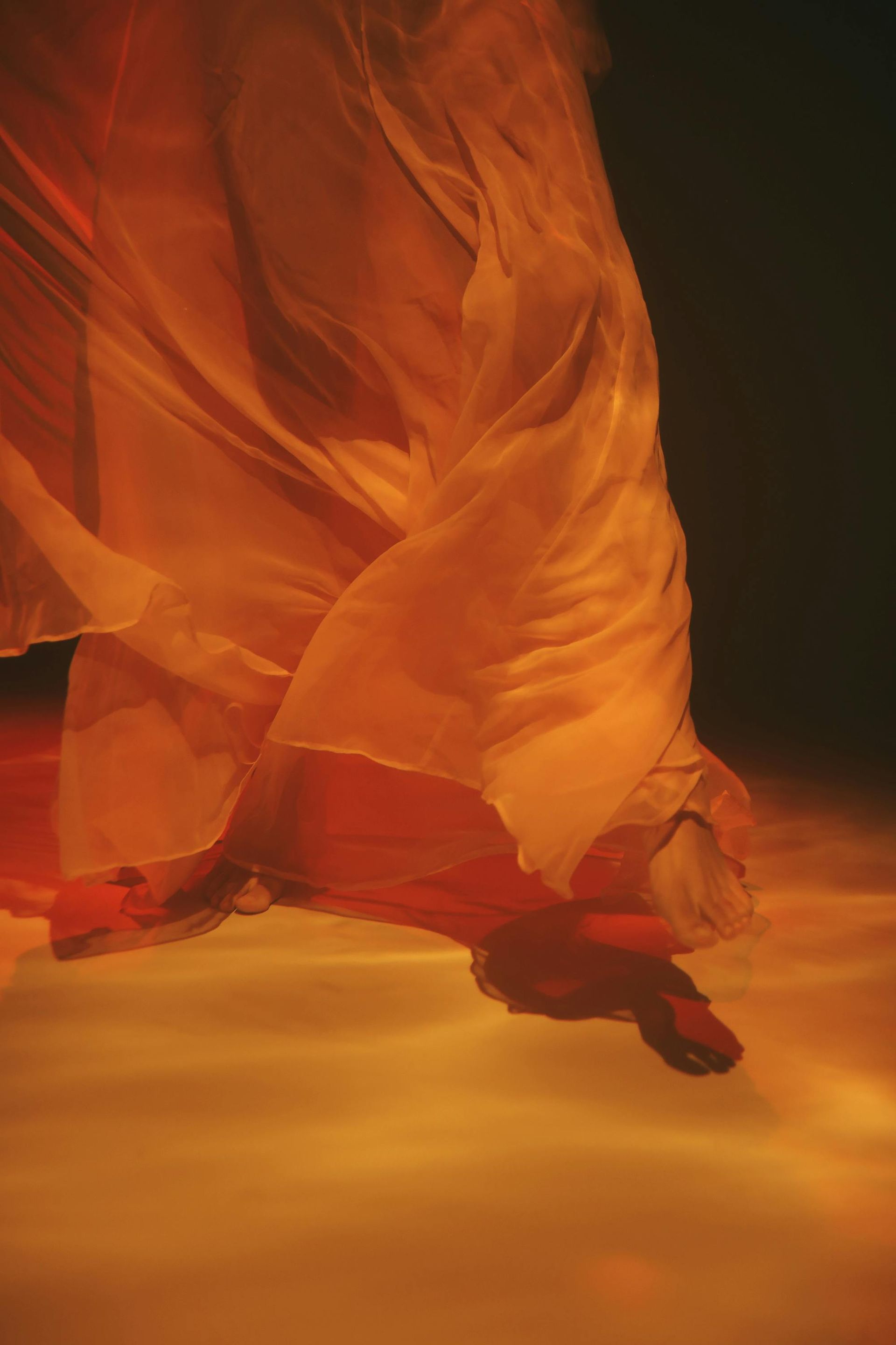 A woman in a long dress is dancing in a dark room.