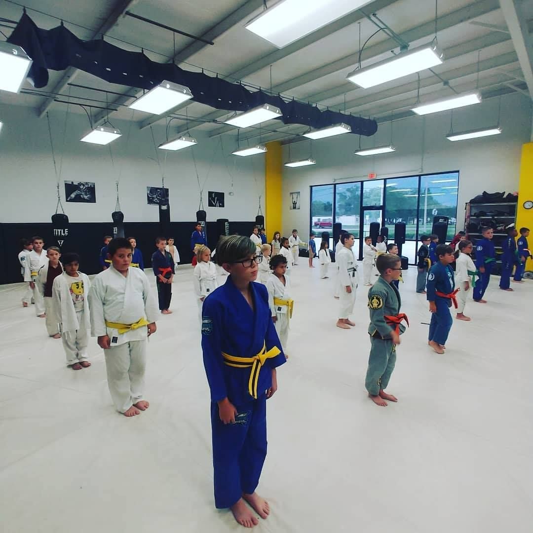 A group of kids are practicing martial arts in a gym