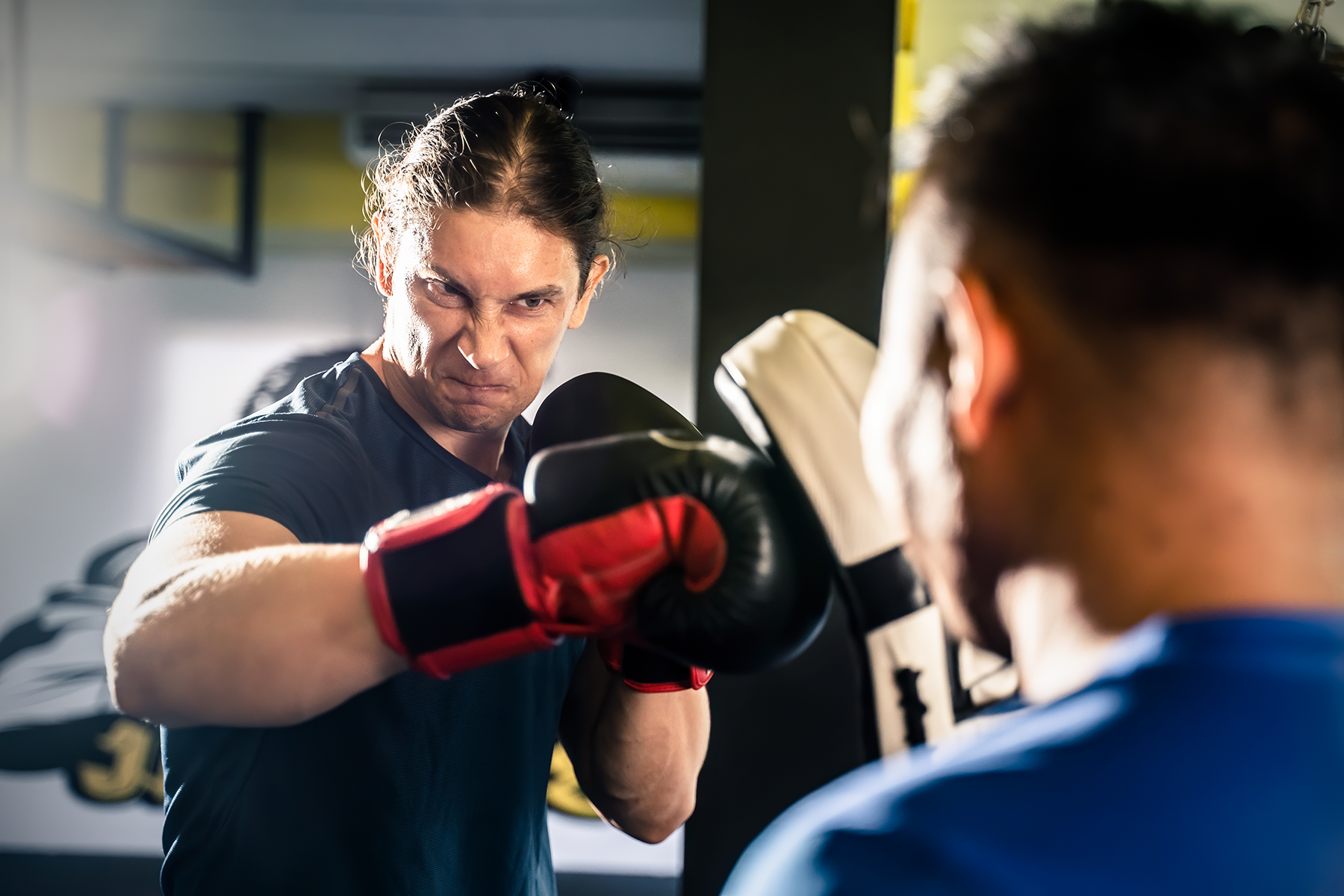 A man is boxing in front of a mirror in a gym.