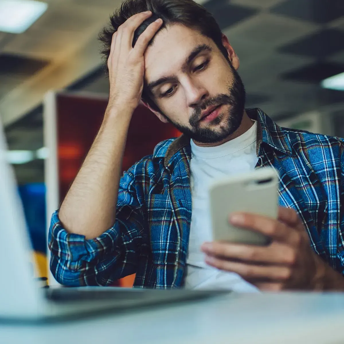 A man in a plaid shirt is looking at his phone