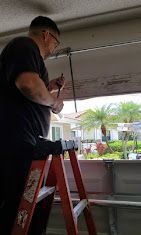 A man is standing on a ladder fixing a garage door.