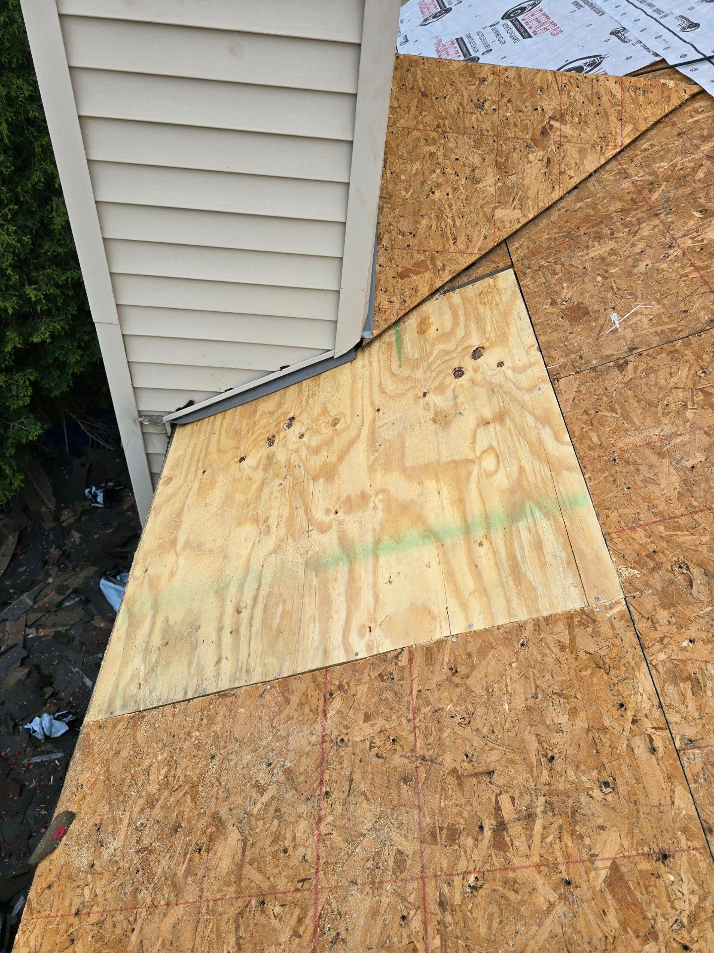 Newly installed plywood roof sheathing around a chimney, showing new wood contrasting with existing oriented strand board.