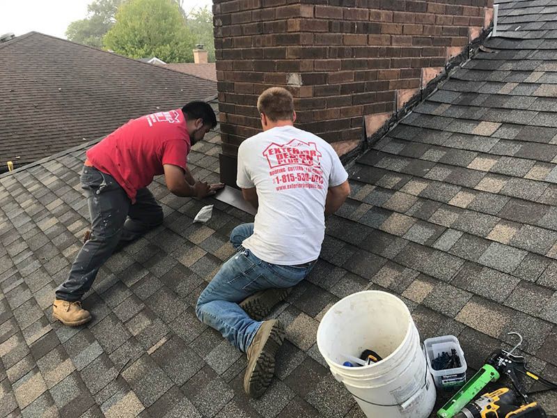 Two men are working on the roof of a house.
