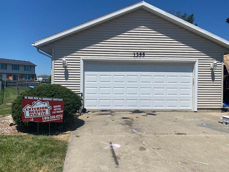 A house with a garage door and a sign in front of it.