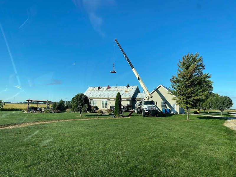 A crane is working on the roof of a house.