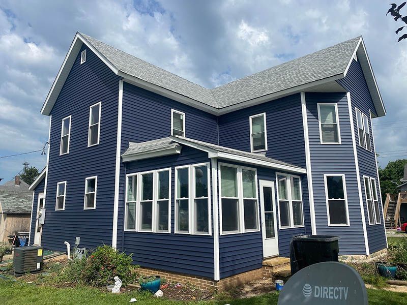 A large blue house with a satellite dish in front of it.