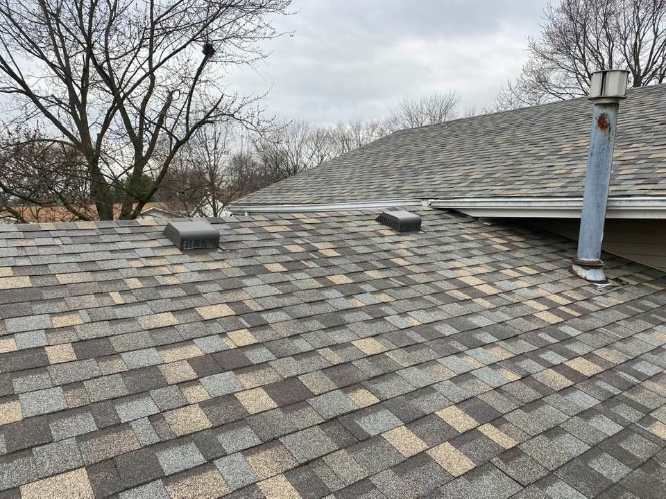 A roof with a lot of shingles on it and trees in the background.