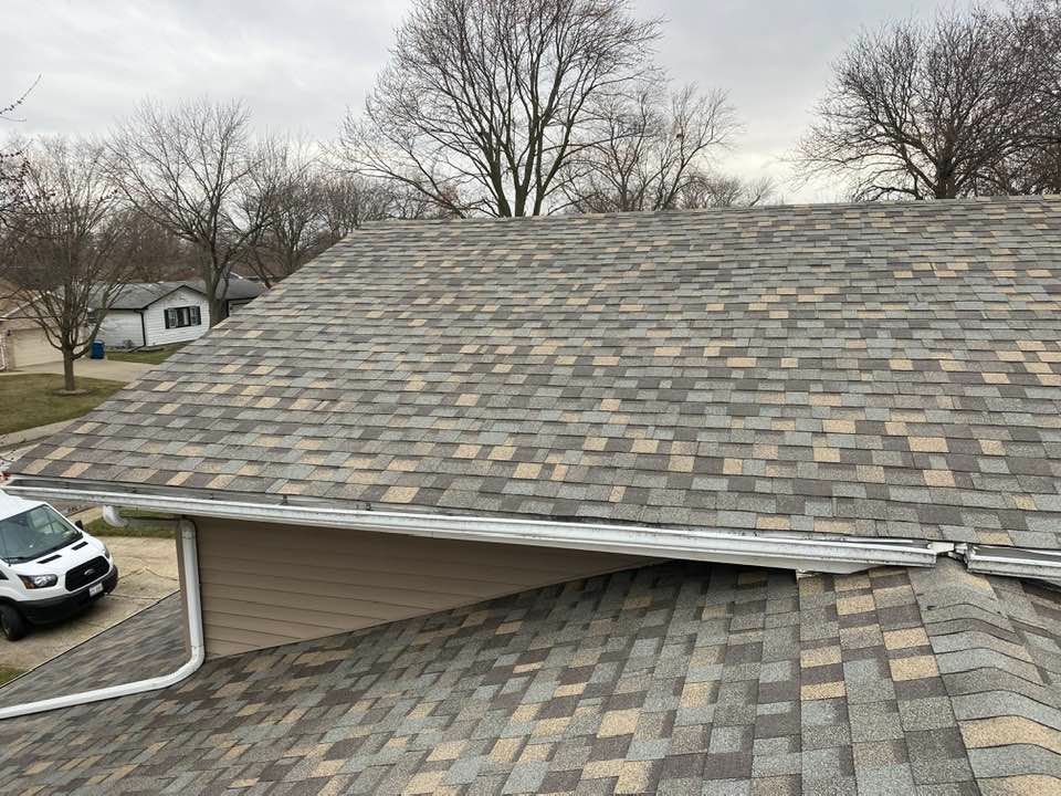 A white van is parked on the side of a house next to a roof.