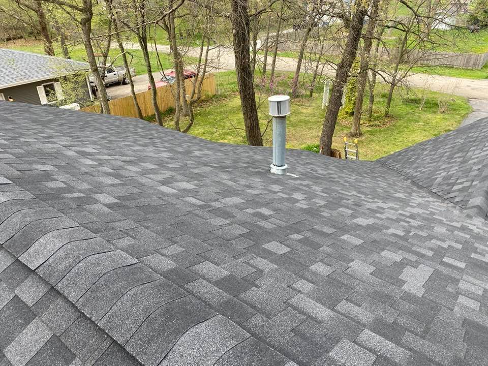 A roof with a chimney on it and trees in the background.