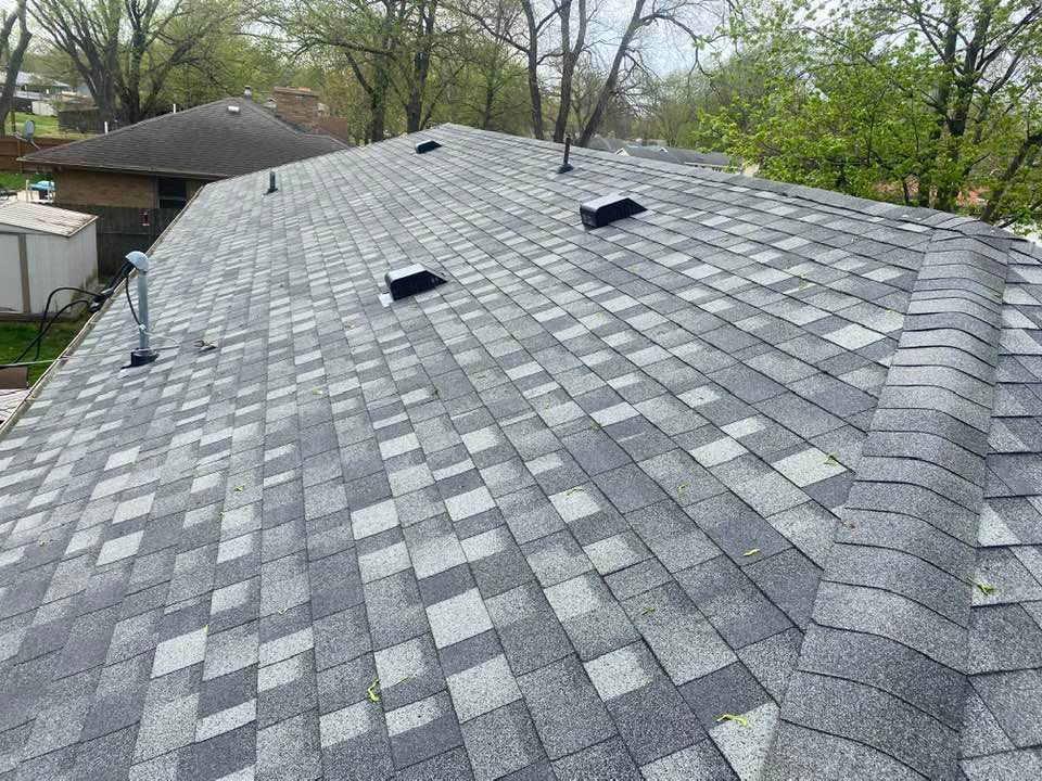 A roof with a lot of shingles on it and trees in the background.