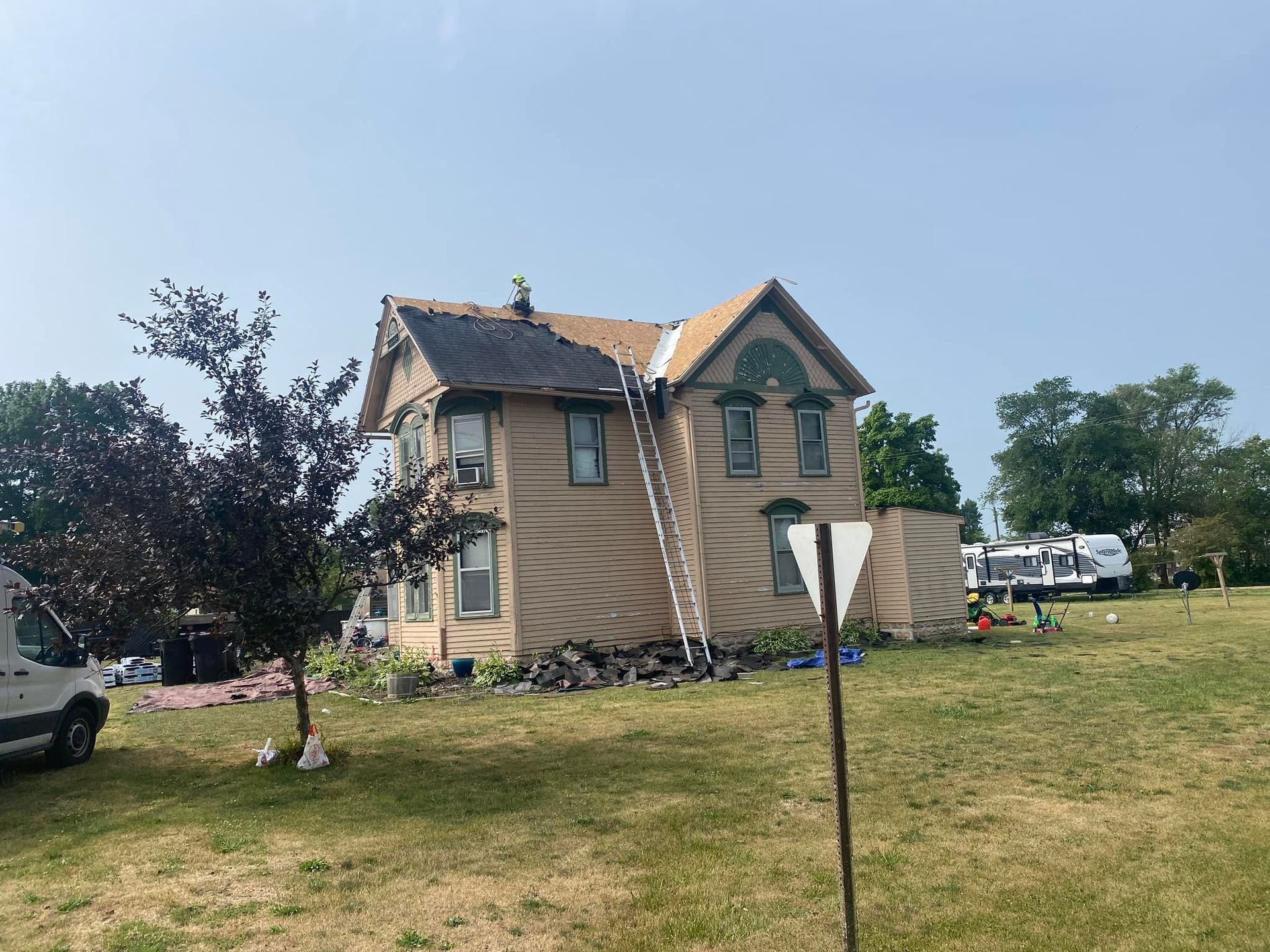 A house with a ladder on the roof is being remodeled.